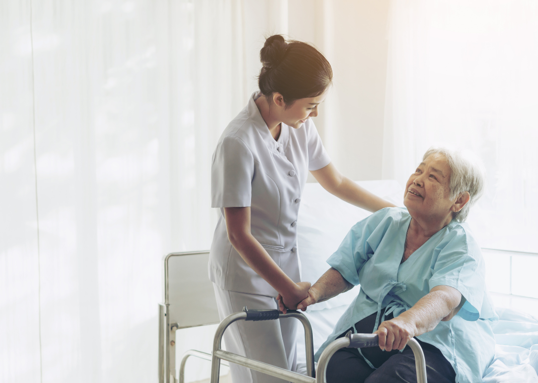 A nurse helping an elderly patient with a walker.