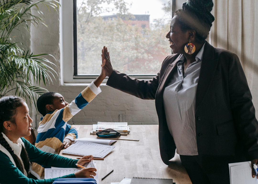 A tutor high-fiving a student during a session with two kids.