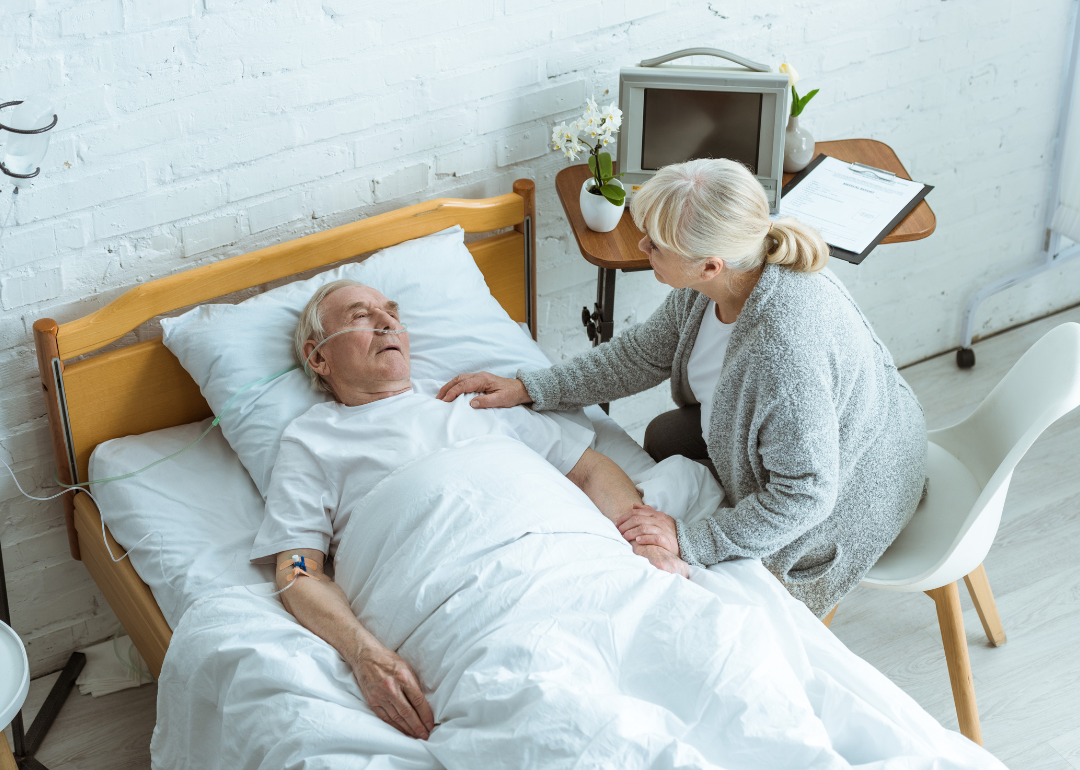 A person visiting an elderly patient in a coma. 