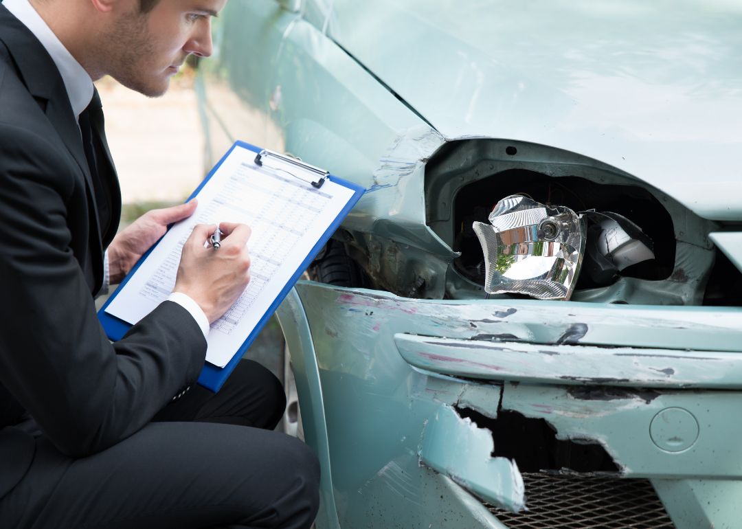 An insurance agent assessing a car after an accident.