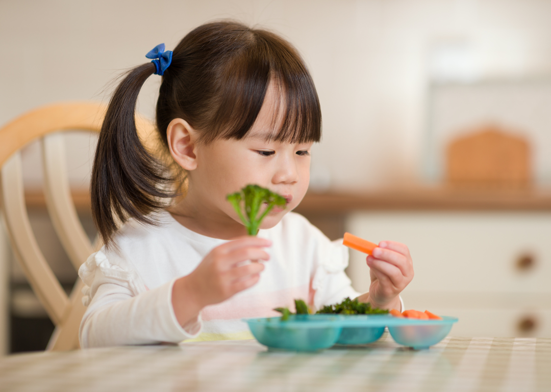 A toddler eating vegetables.