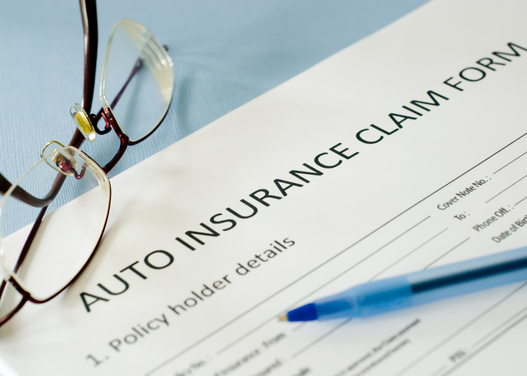 An auto insurance claim form with glasses and a pen on it.