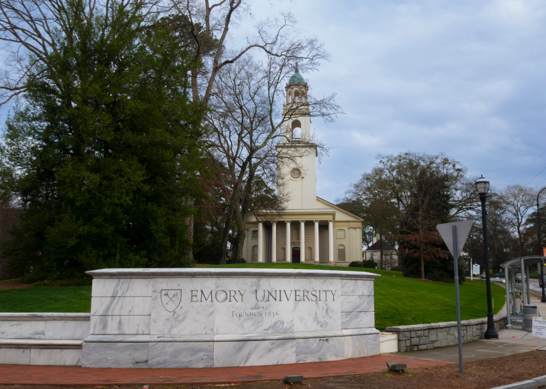The entrance sign for Emory University with buildings in the background.