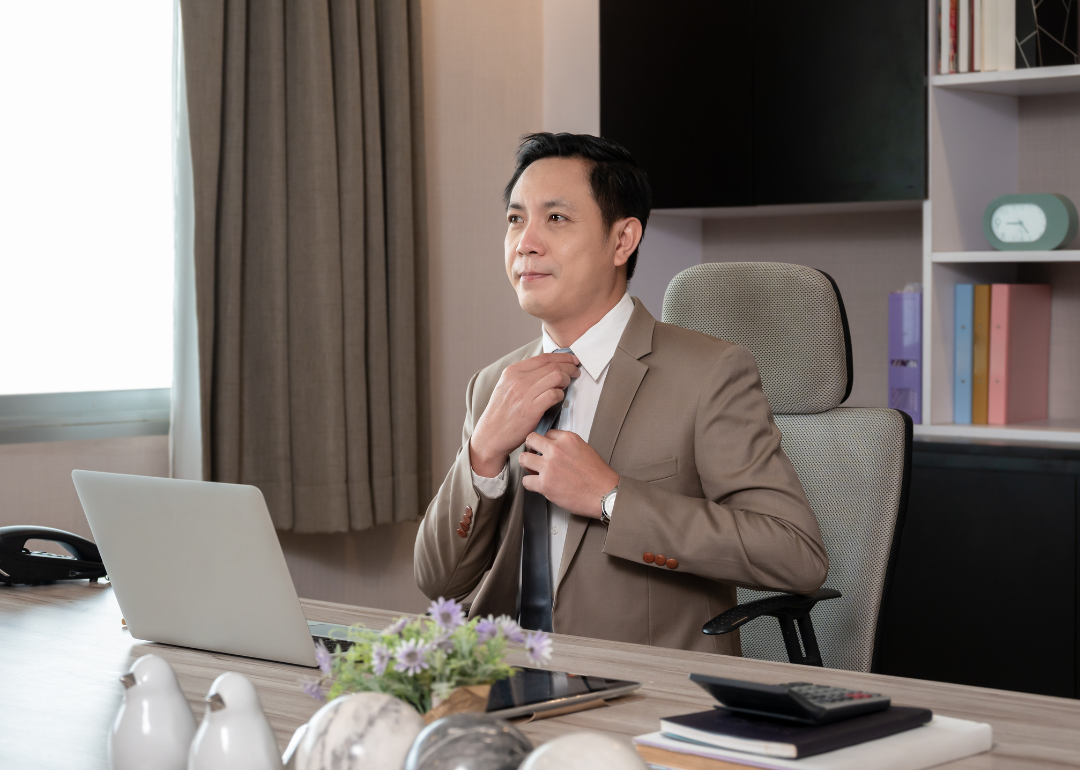 A businessperson adjusting their tie while inside their private office.