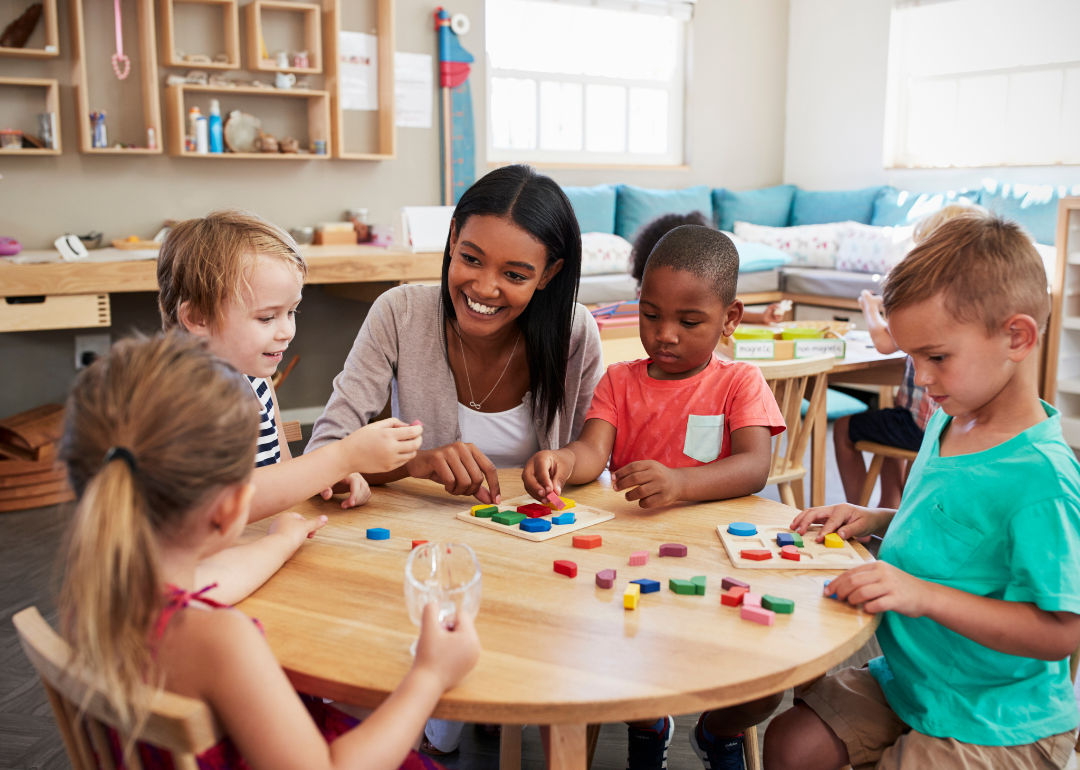 A tutor working with a group of four kindergarten students on identifying shapes.