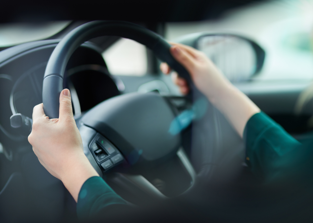 A person with their hands on the wheel of a car.