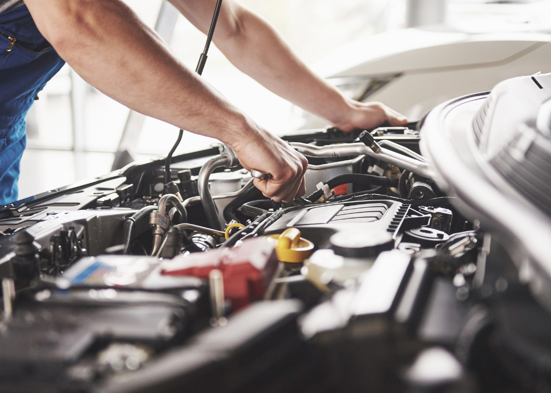 A person checks a car engine.