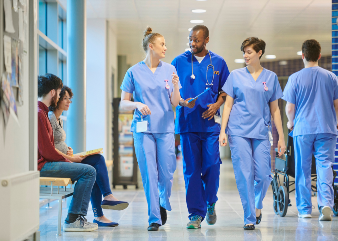 A group of doctors speaking as they walk down a hospital hallway.