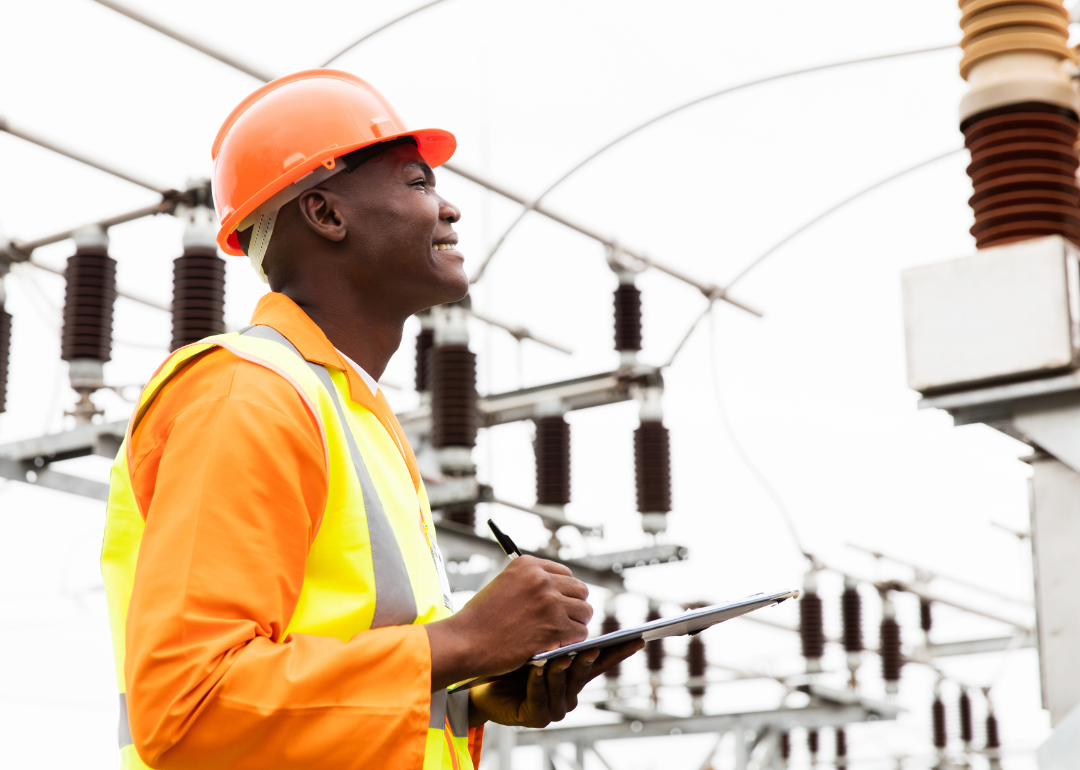 An electric worker taking notes on a clipboard.