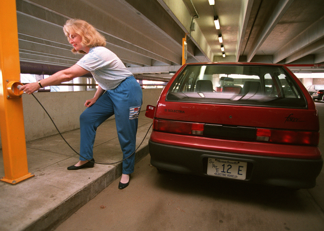 A woman plugging in her Geo Metro car.