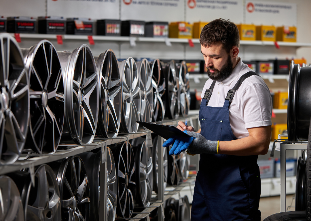 Salesperson looks at tires in auto parts store