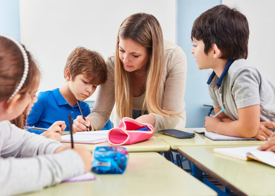 A teacher tutoring a group of four elementary-aged students.