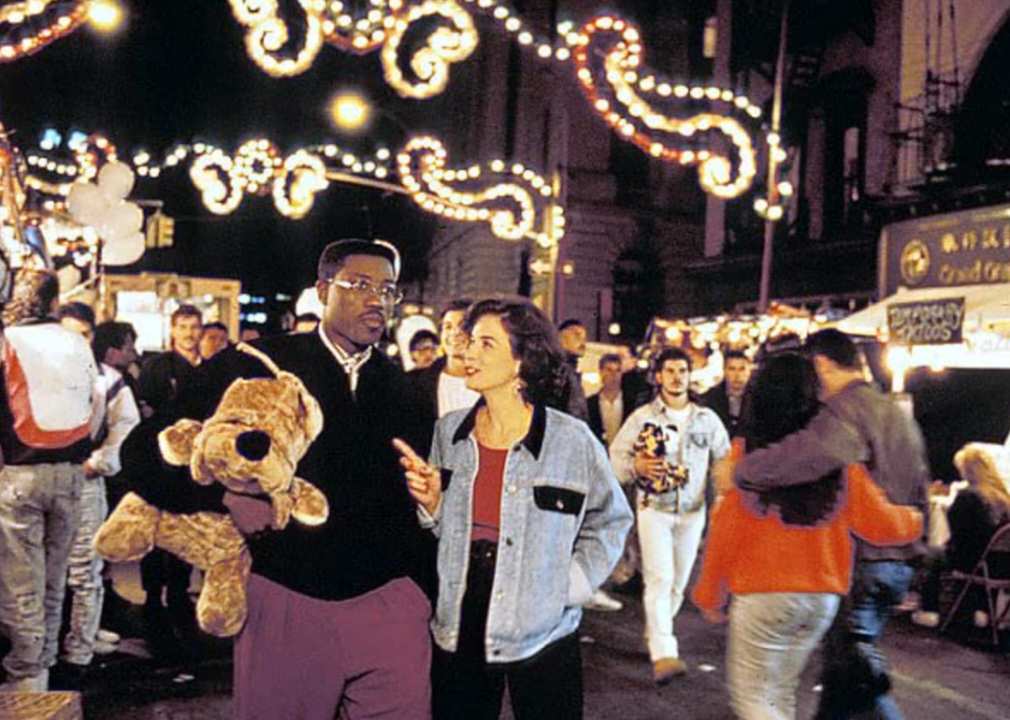 Wesley Snipes and Annabella Sciorra walk through a busy street carnival during a scene in the film, Jungle Fever.