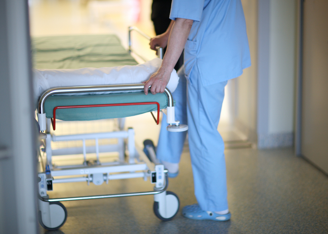 An orderly moves a hospital bed.