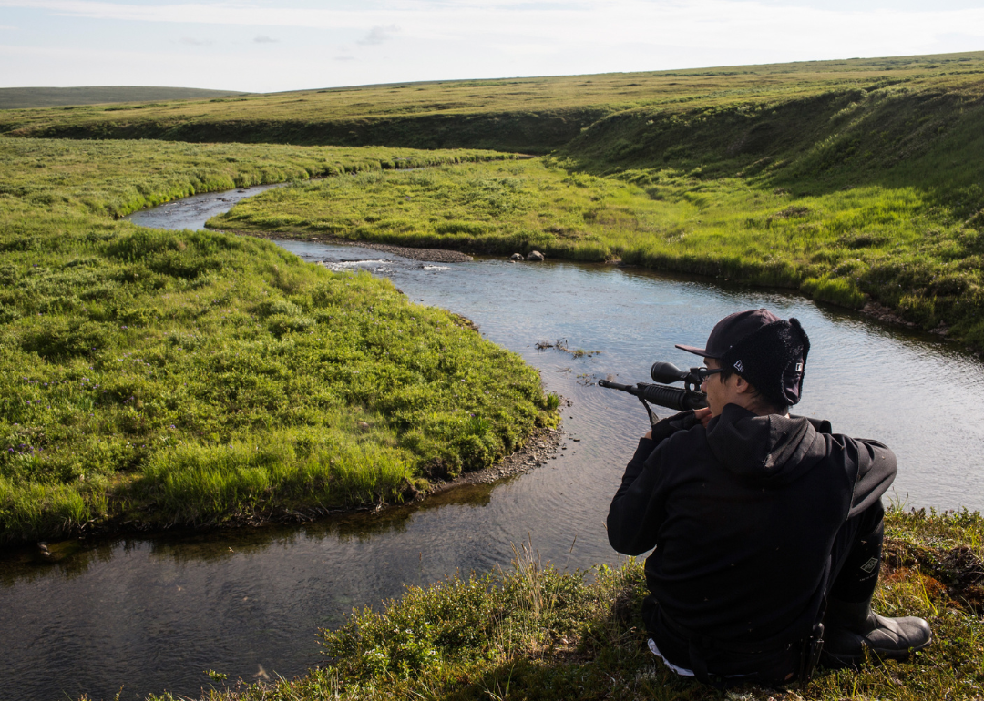 A person tracking a musk ox with a rifle during a hunting expedition on Nelson Island.