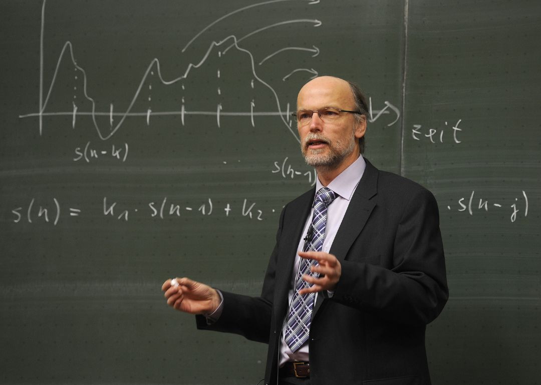 A professor solving a math equation on a blackboard.