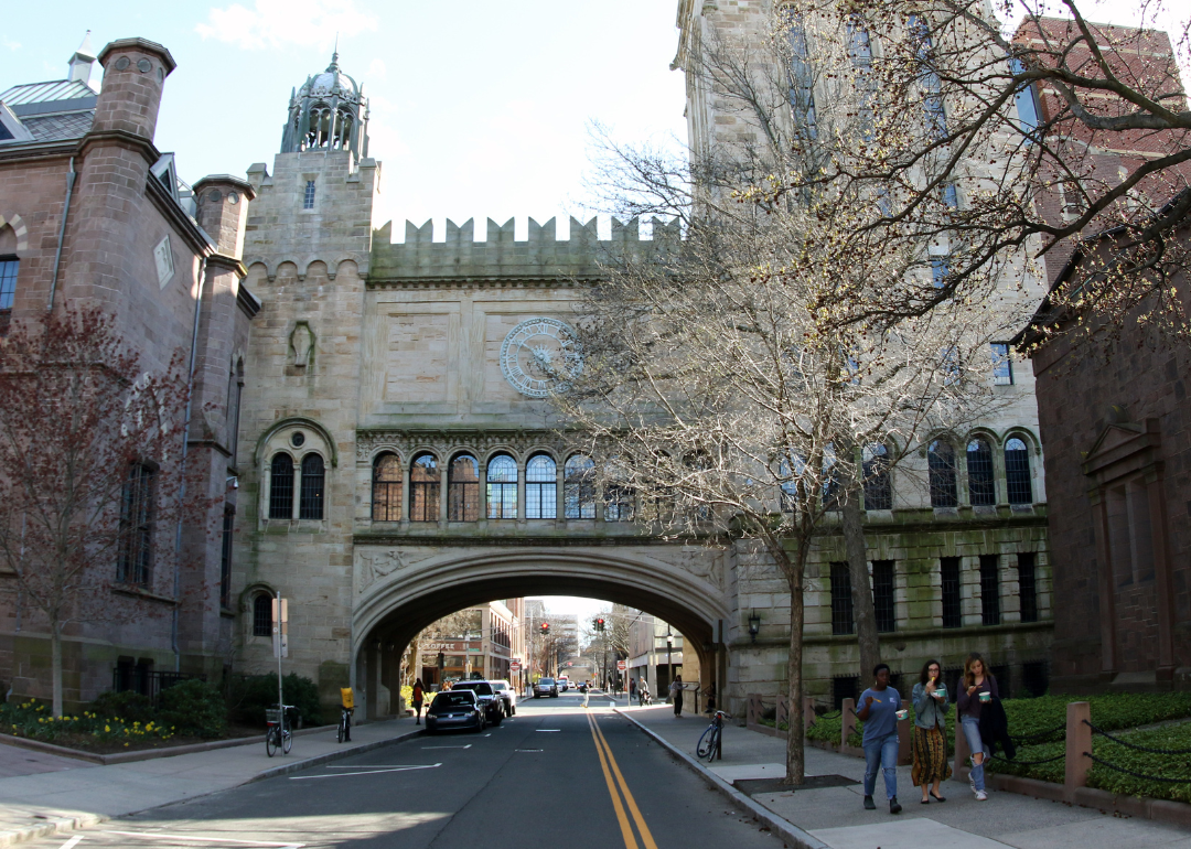 Three students walking under High Street Arch at Yale University in New Haven, Connecticut.