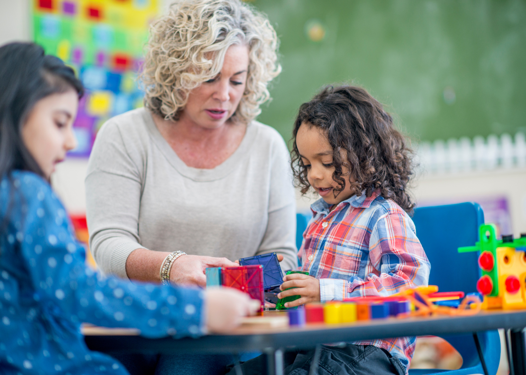 A preschool teacher works with a student.