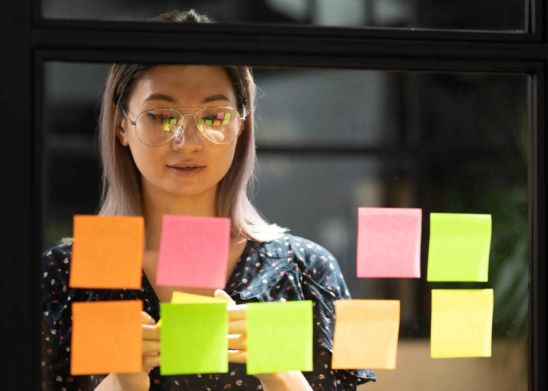 An employee studies Post-Its that are arranged on window.