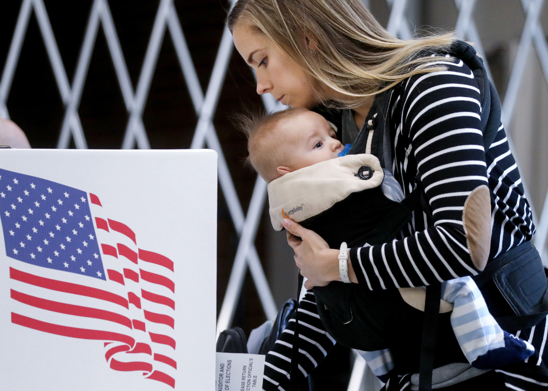 A voter holding a baby while completing a ballot in Des Moines, Iowa