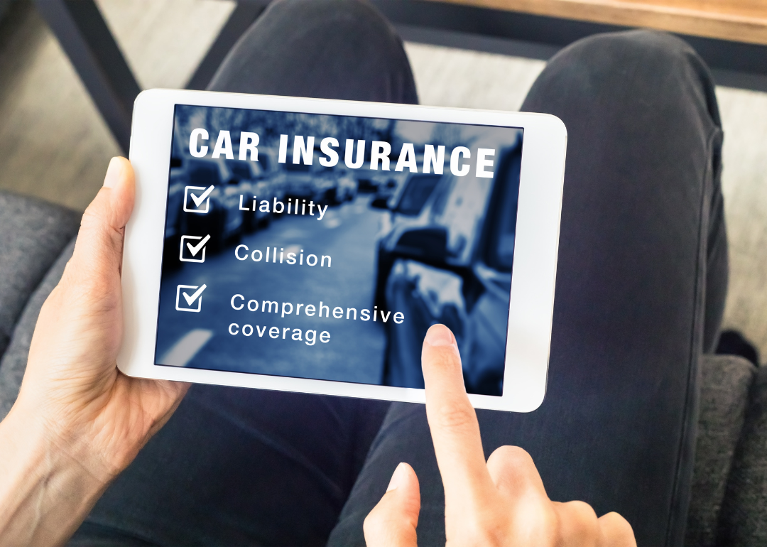 A person holding a tablet to select a type of auto insurance, given the options of liability, collision, and comprehensive coverage.