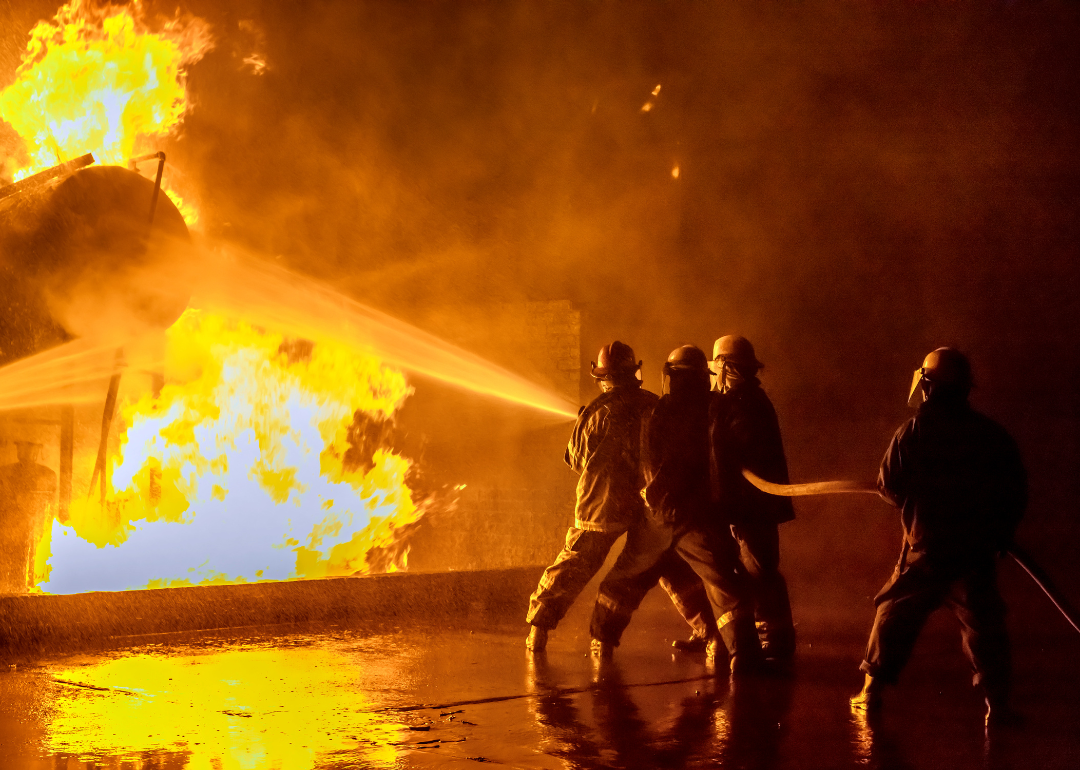 Firefighters using a hose to extinguish an industrial fire.