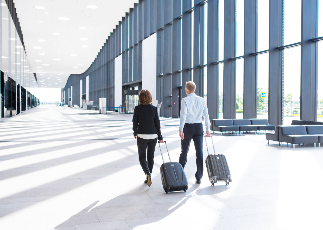 Business people in formal clothing walking with wheeled bags at an airport terminal