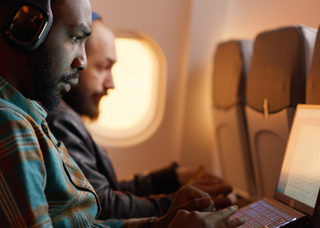 A businessperson using their laptop while on a flight for a work trip