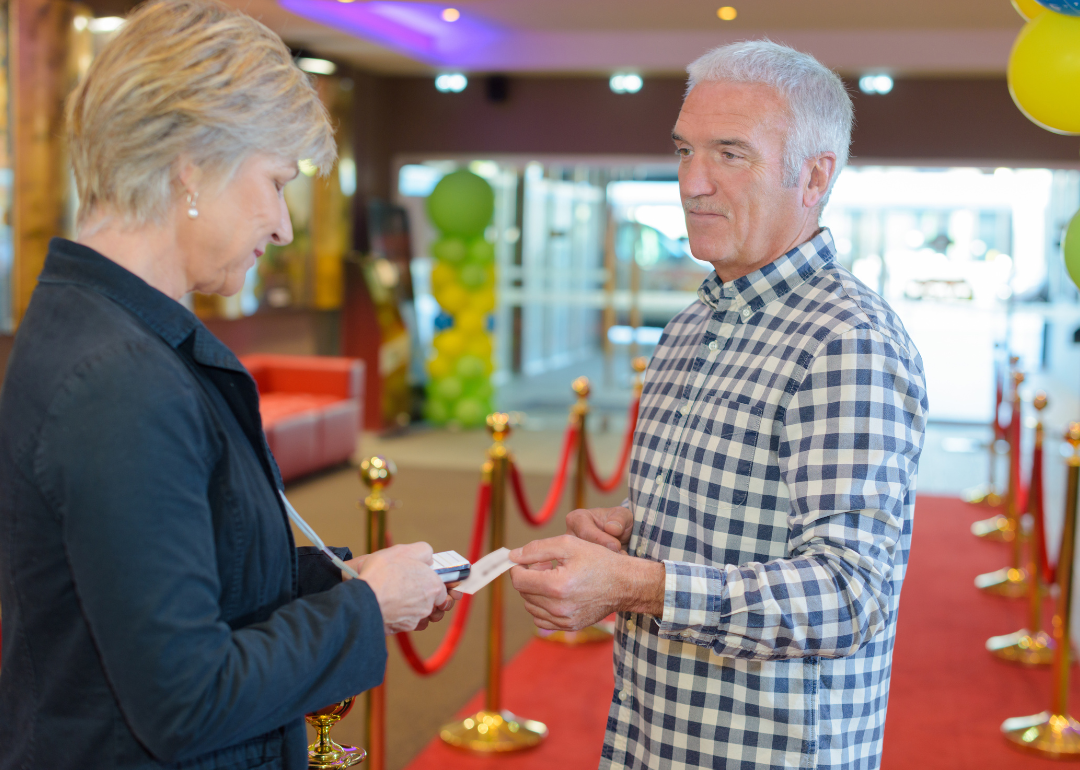 A man giving his ticket to a woman in the lobby of a theater