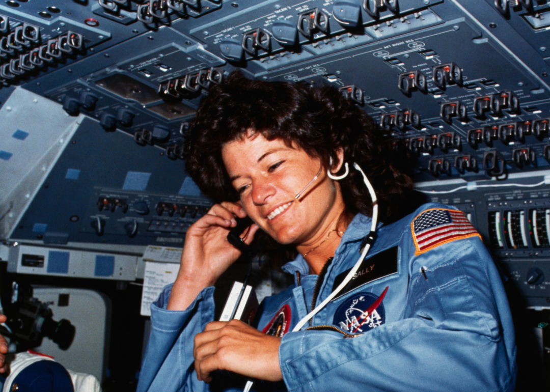 Astronaut Sally K. Ride communicating with ground controllers from the flight deck of the Earth-orbiting Space Shuttle Challenger.