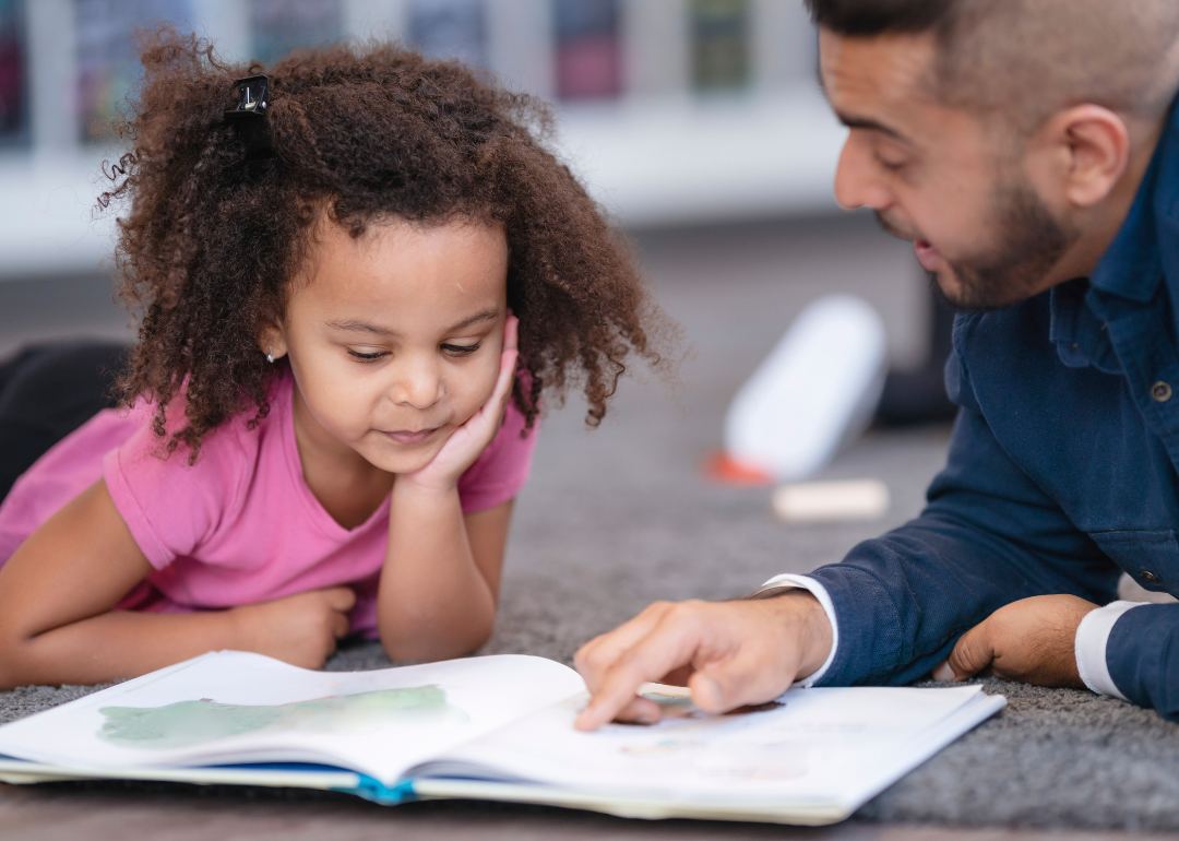 A kindergarten teacher reading a book to a student.