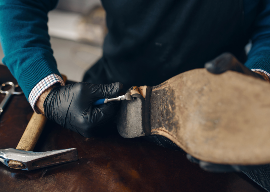 A shoe repairer fixes a sole.