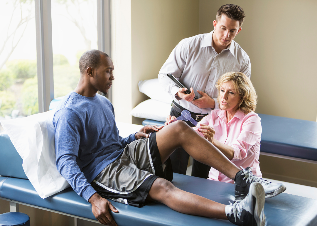 Two physical therapists examining a patient's leg.
