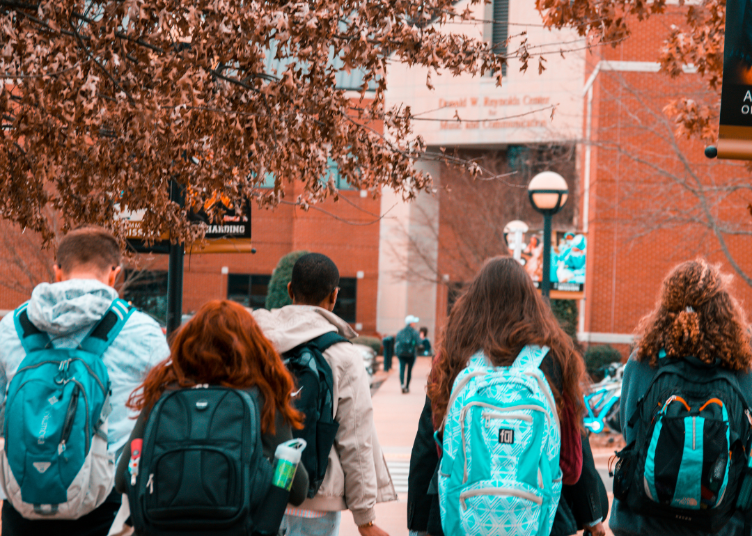 College students wearing backpacks walking toward an academic building.