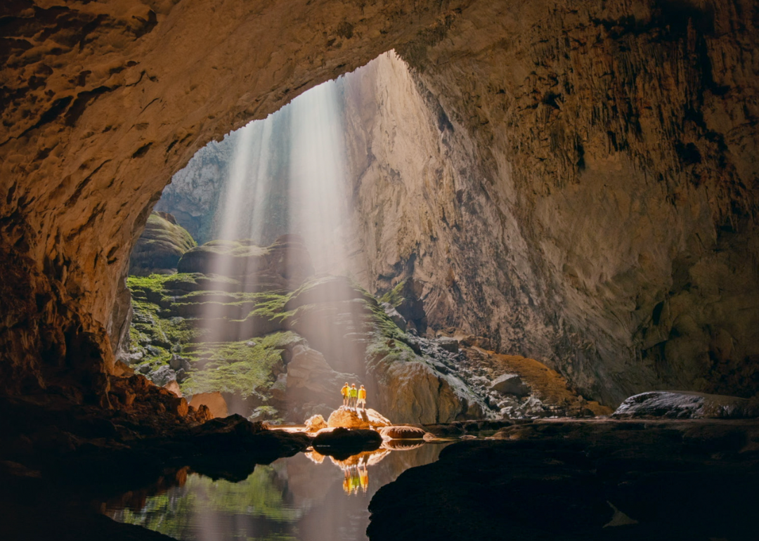 People standing in a cavern as light shines in