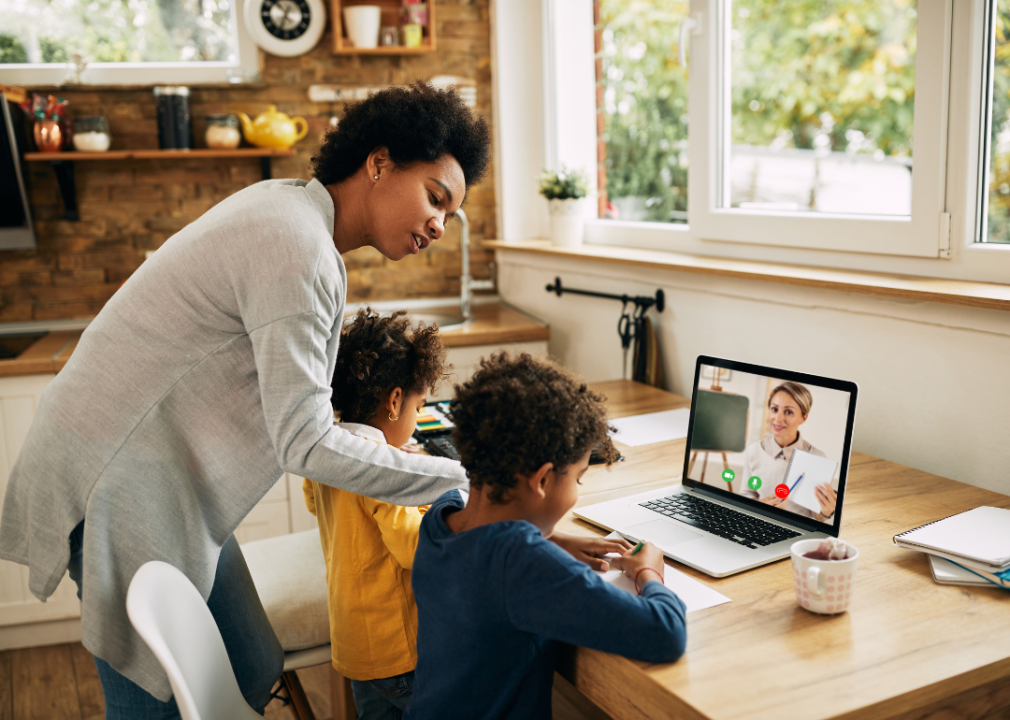 A parent hovering over her children while they attend class remotely