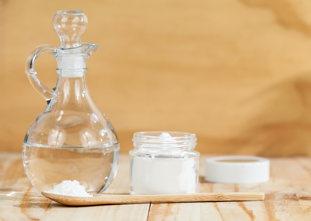 Baking soda and white vinegar on a wooden table.