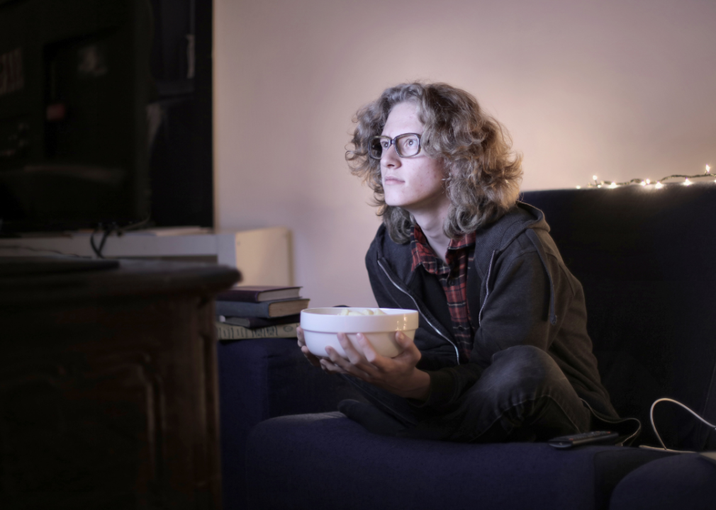 An interested teenager watching TV with popcorn