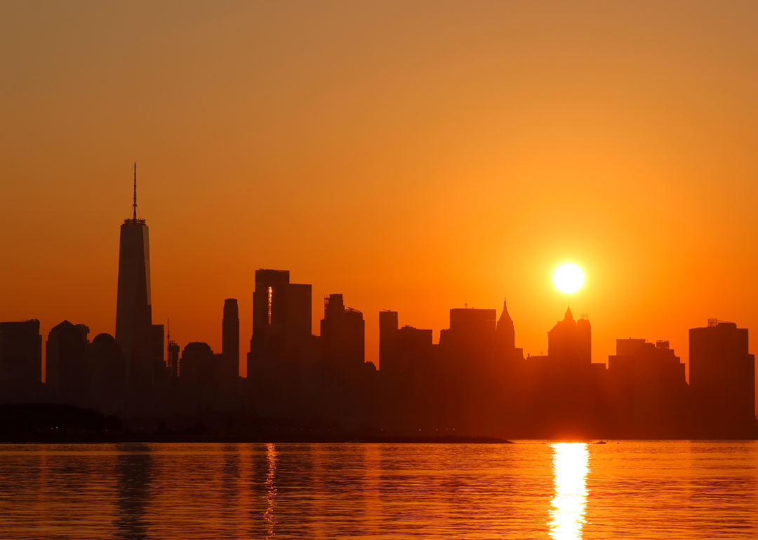 The sun rising behind lower Manhattan and One World Trade Center as a heatwave continues in New York City on July 23, 2022
