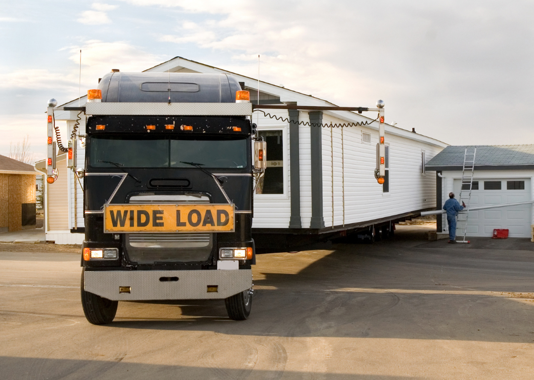 A flat bed hauler carries a manufactured home.