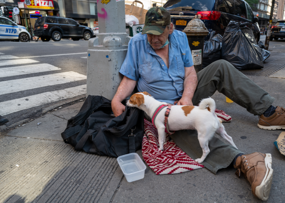 John, who is homeless, sitting with his dog Daisy on a Manhattan street during a heat wave on July 22, 2022, in New York City