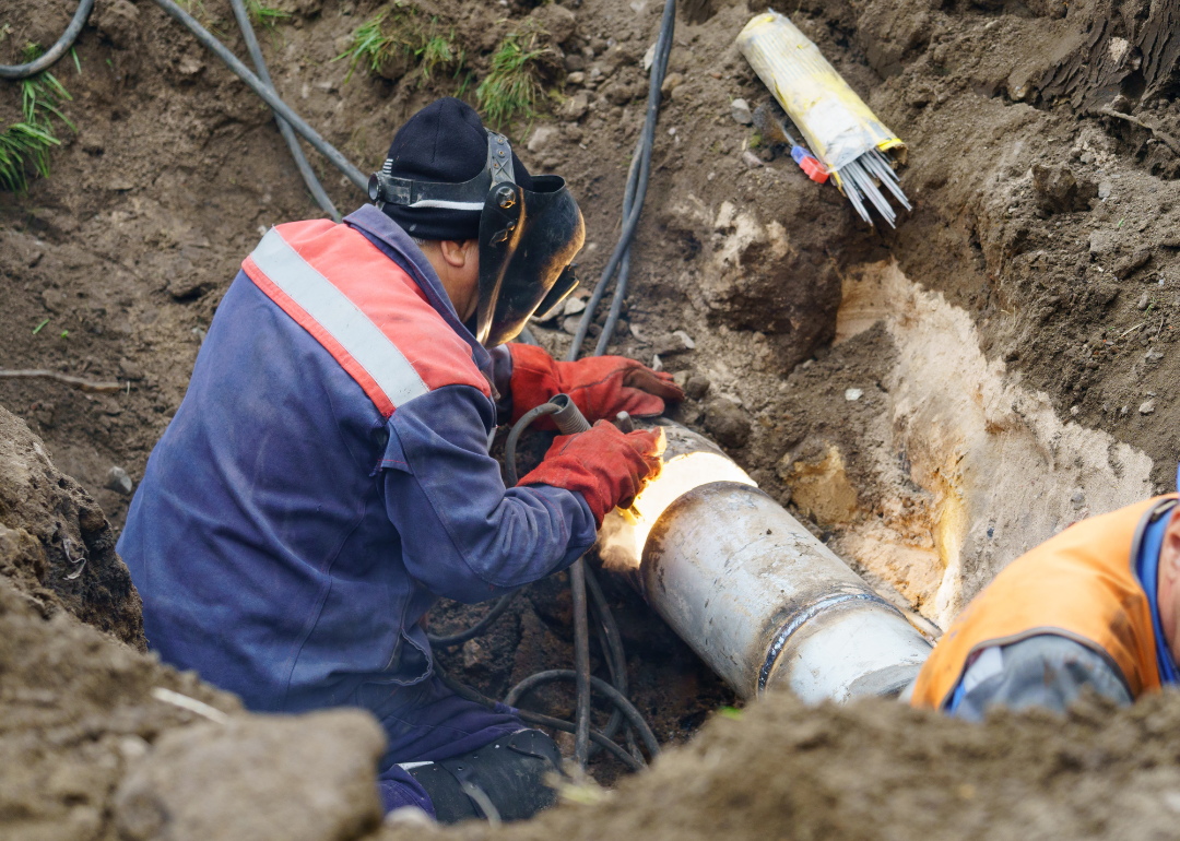 A utility worker fixing a broken water main.