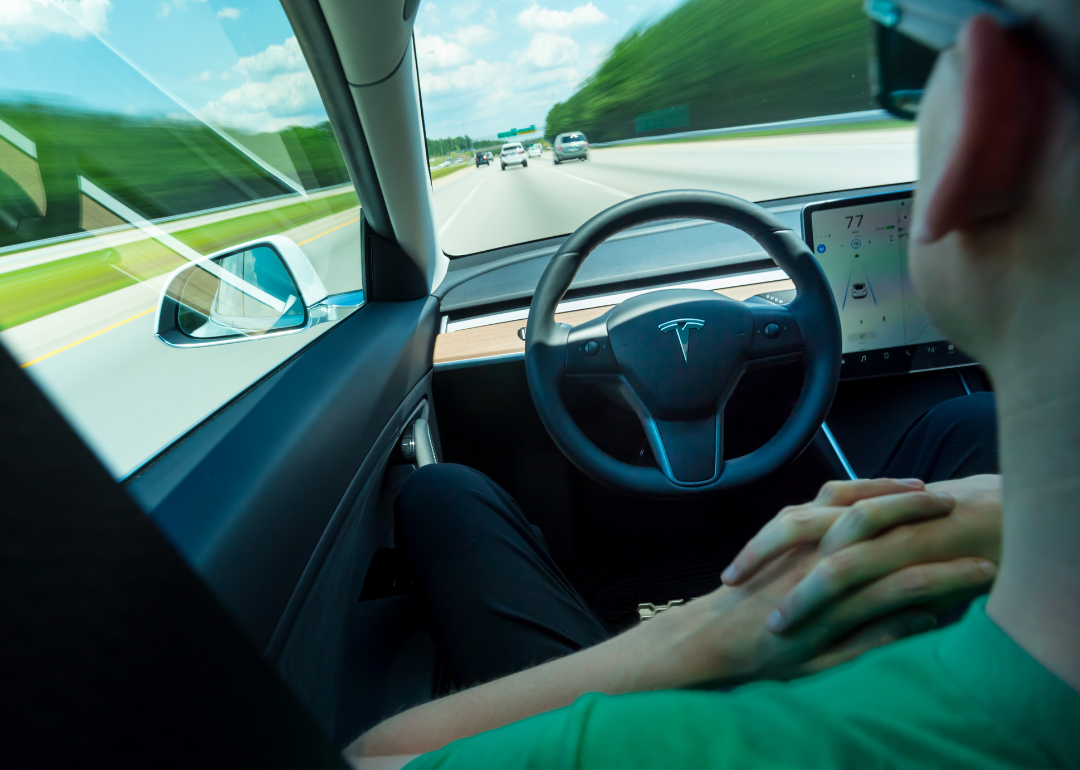 A person using the autopilot self-driving function in an all electric Tesla Model 3