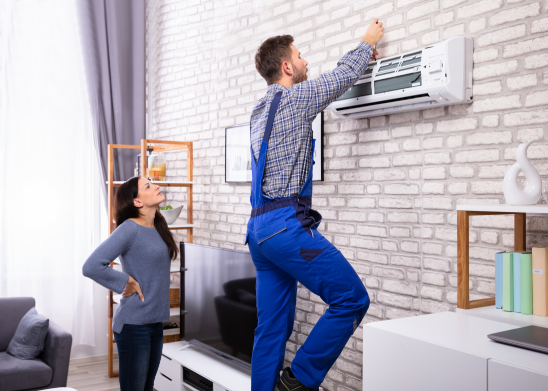 A homeowner watching a technician install an air conditioner.
