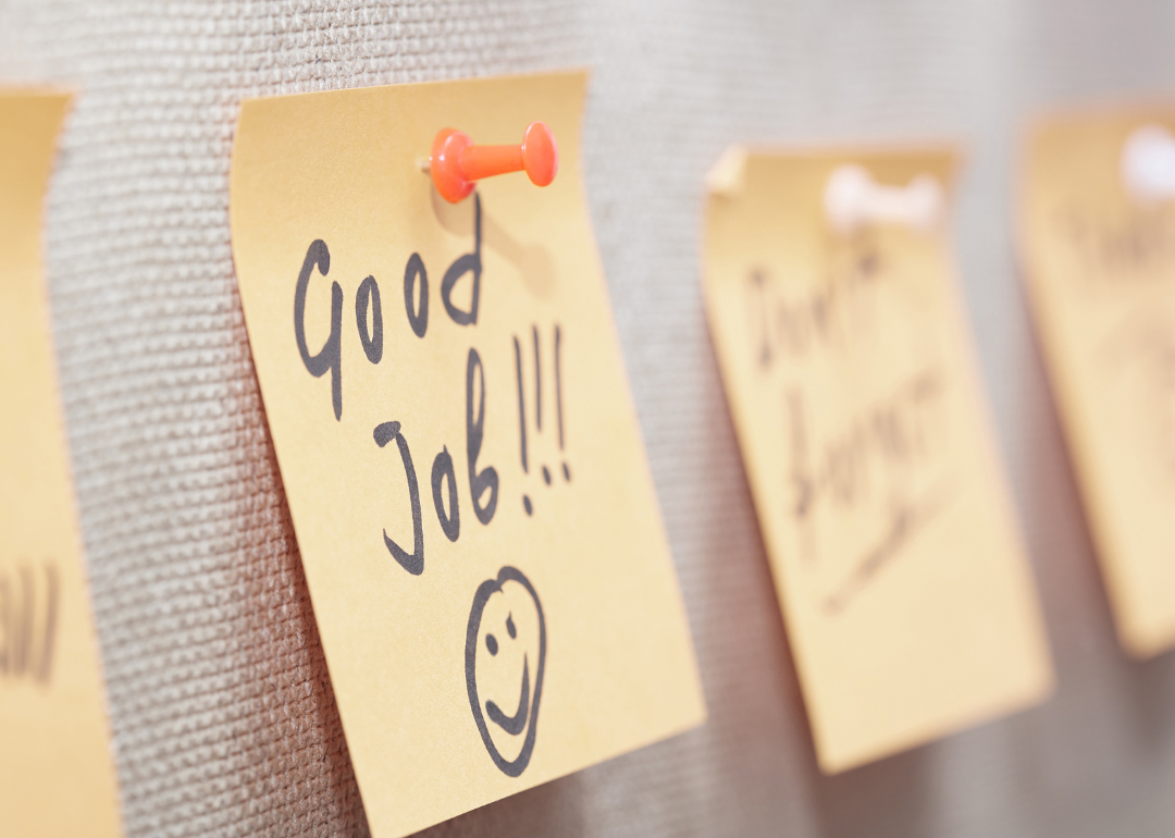 An adhesive note with "Good Job" written on it on a cork bulletin board.