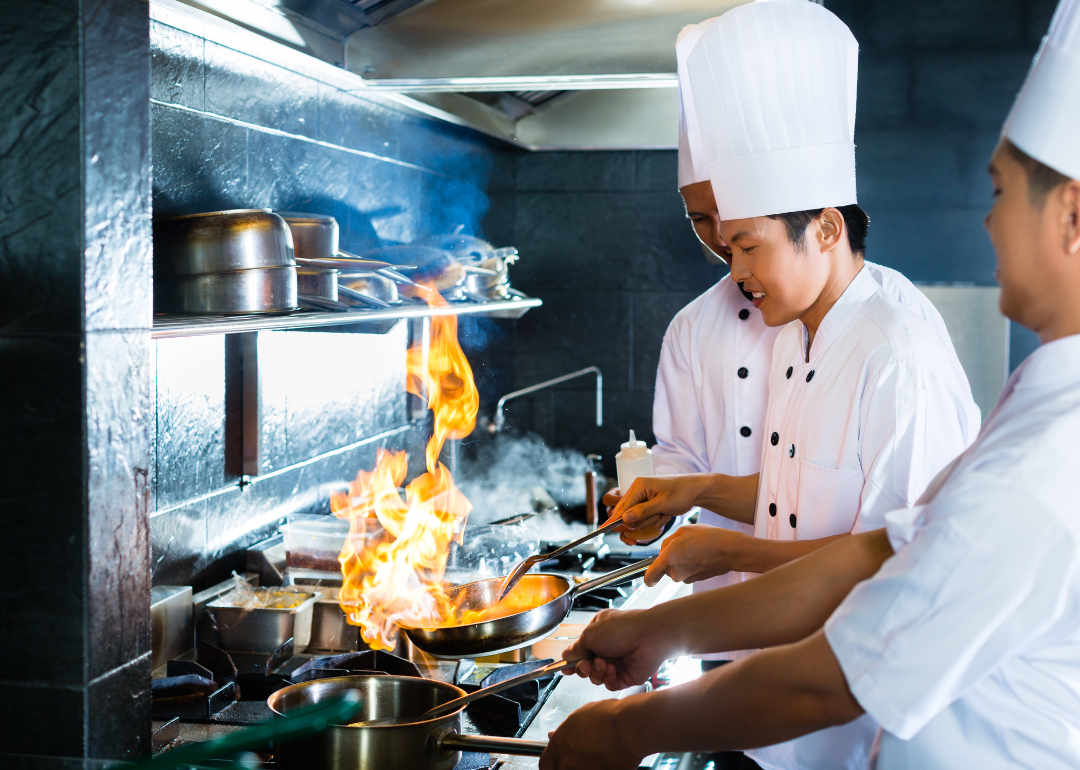 A restaurant cook works over a hot flame.