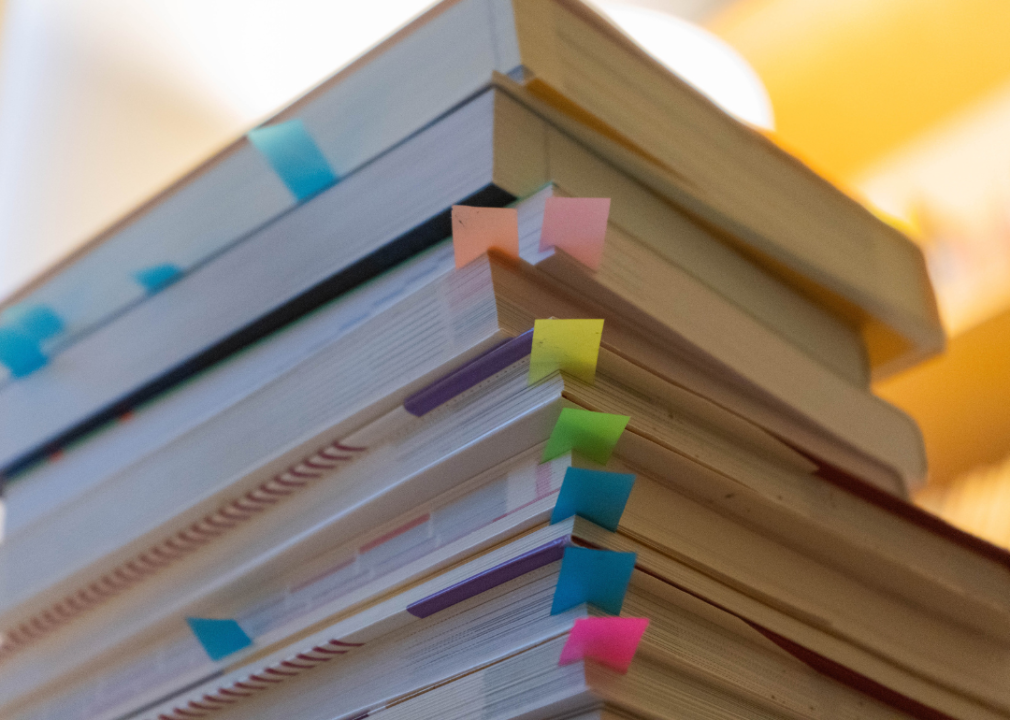 A pile of textbooks that are flagged with sticky notes