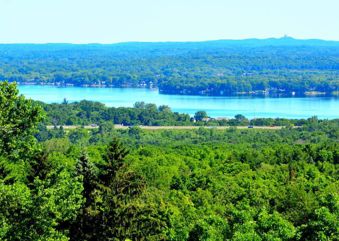 Pewaukee Lake surrounded by lush, green forest.