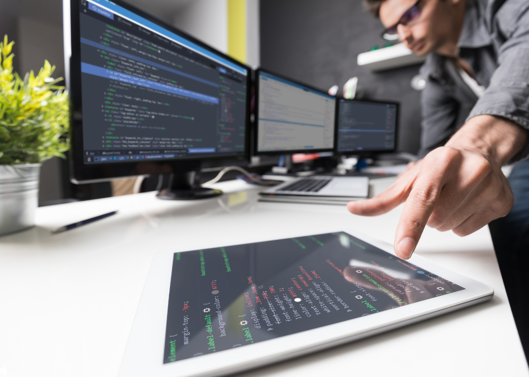 Two computer system technologists designing a system using desktops and a tablet.