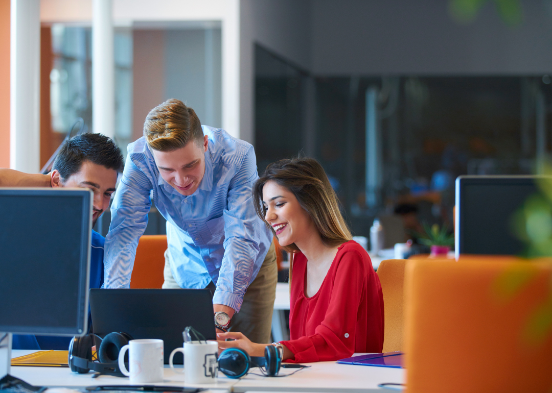 A group of office workers smiling while working together.